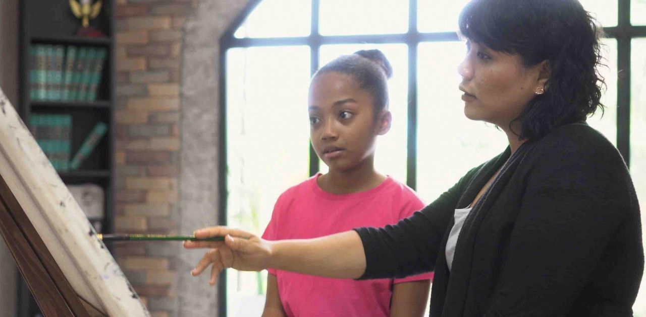 Woman teaching young girl to paint