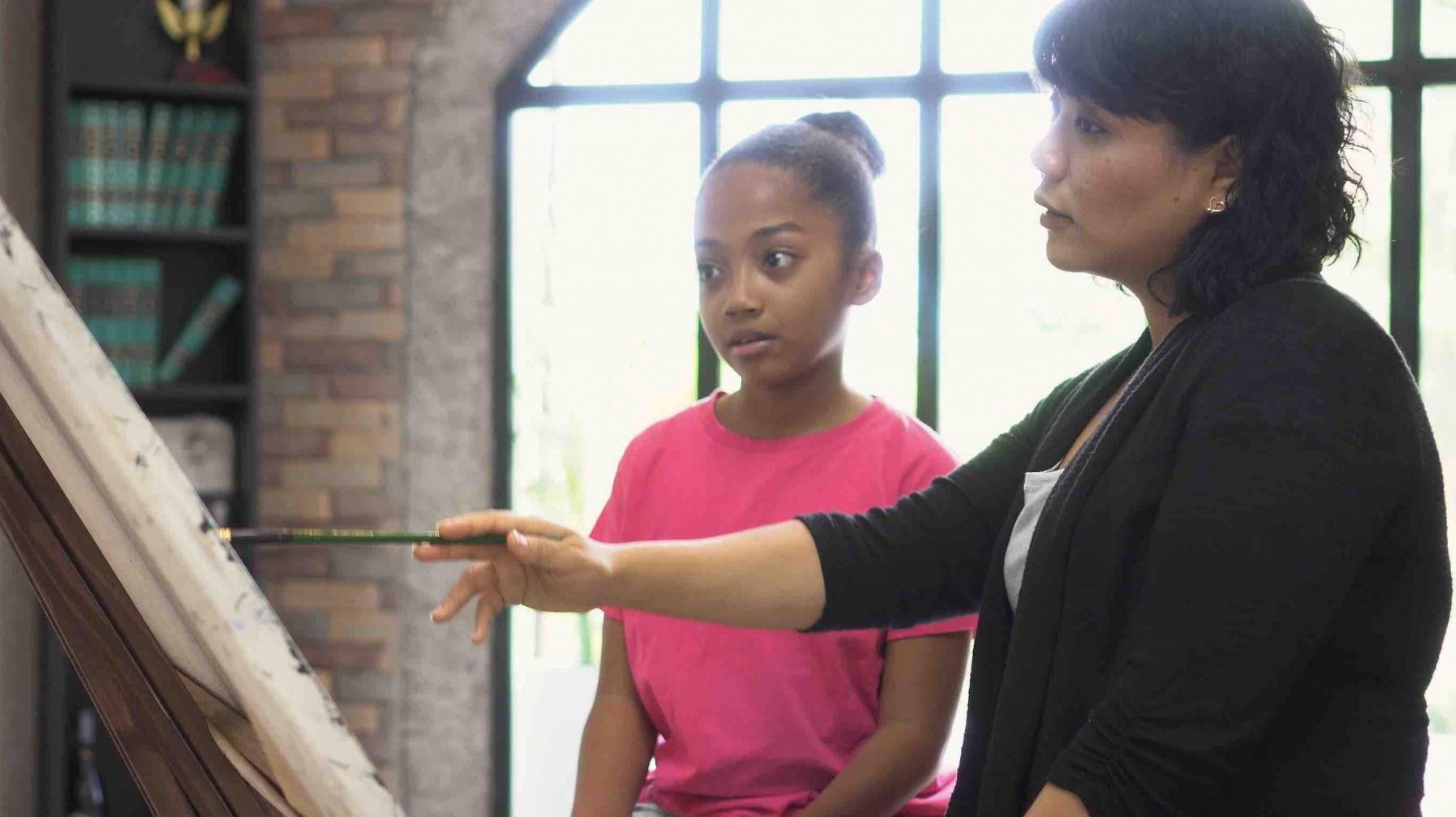 Woman teaching young girl to paint