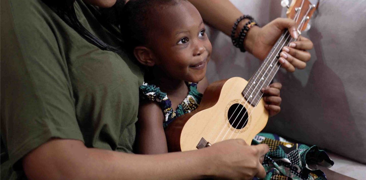 Little girl and woman play the ukulele