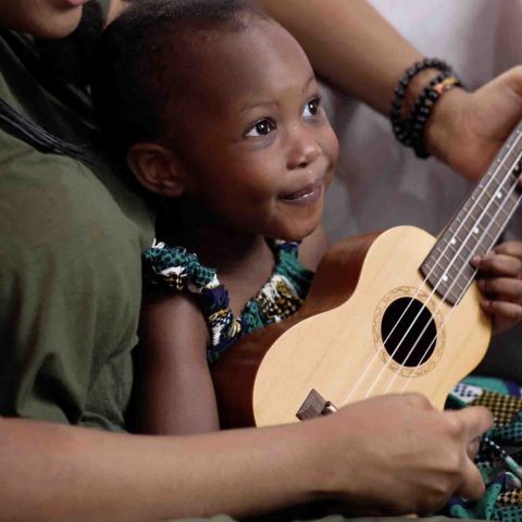 Little girl and woman play the ukulele